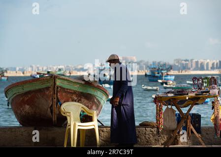 Alexandrie, Égypte. 1 décembre 2022 une cabine souvenir touristique informelle à côté d’un bateau de pêche sur le front de mer méditerranéen de la deuxième plus grande ville d’Égypte Banque D'Images