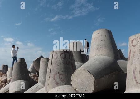 Alexandrie, Égypte. 1 décembre 2022 de jeunes Egyptiens prennent des photos sur des blocs de béton massifs conçus pour protéger le front de mer Méditerranée de Banque D'Images