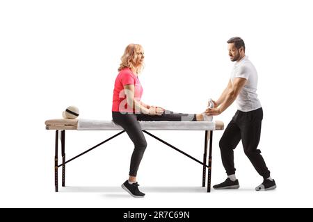 Thérapeute en réadaptation physique traitant une femme mature avec une jambe blessée isolée sur fond blanc Banque D'Images