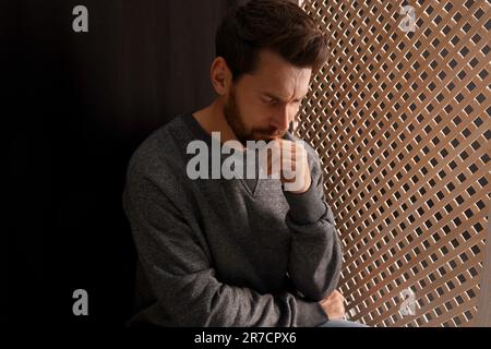 Énervé homme à l'écoute du prêtre pendant la confession dans le stand Banque D'Images