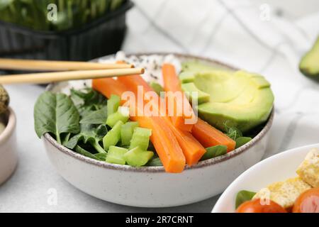 Délicieux poke Bowl avec basilic, légumes et avocat sur table gris clair, gros plan Banque D'Images