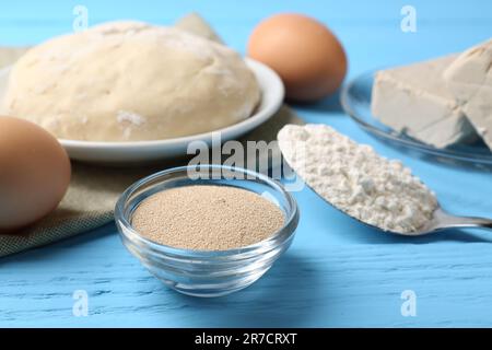 Différents types de levure, oeufs, pâte et farine en cuillère sur table en bois bleu clair Banque D'Images