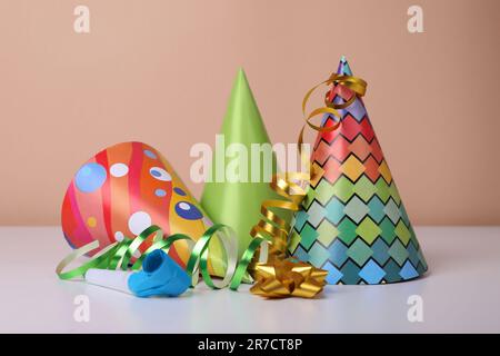 Chapeaux de fête colorés, banderoles et souffleur sur table blanche. Fête d'anniversaire Banque D'Images