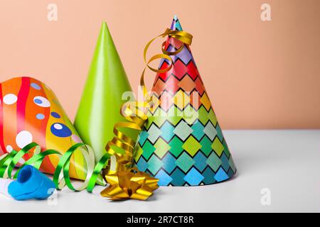 Chapeaux de fête colorés, banderoles et souffleur sur table blanche, espace pour le texte. Fête d'anniversaire Banque D'Images