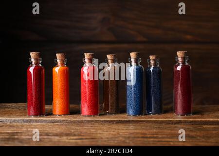 Bouteilles en verre avec différentes couleurs alimentaires sur table en bois Banque D'Images