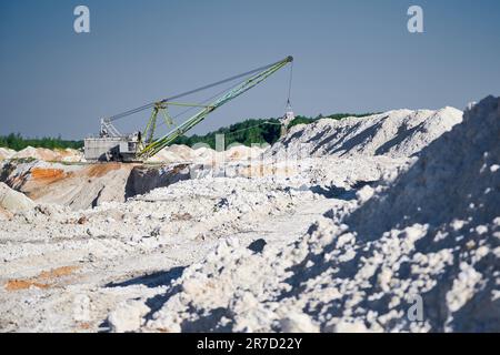La pelle de marche fonctionne près des rangées de pieux dans la fosse minière Banque D'Images