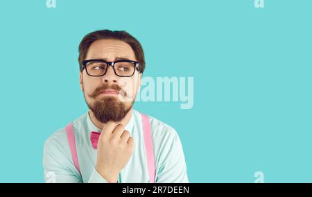 Drôle et élégant homme nerd penser ou prendre des décisions sur fond bleu clair. Banque D'Images