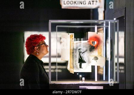 Louisa McGeachie, intendant de la galerie, regarde de plus près le morceau de pochoir de la jeune fille avec le ballon à cœur au nouveau spectacle de l'artiste Banksy 'Cut & Run' qui ouvre ce dimanche à Goma, à Glasgow. révélant pour la première fois les pochoirs utilisés pour créer de nombreuses œuvres les plus emblématiques de l'artiste. Le spectacle comprend des objets authentiques, des éphémères et les toilettes de l'artiste. Il se déroulera pendant trois mois et sera ouvert toute la nuit le week-end. Date de la photo: Jeudi 15 juin 2023. Banque D'Images