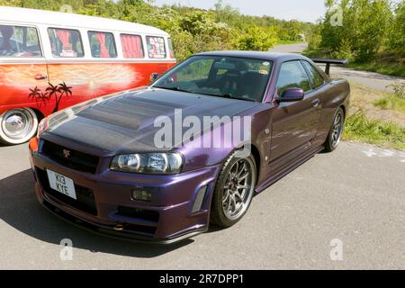 Vue des trois quarts avant d'un coupé Skyline GT-T 2000 violet et R34 de Nissan exposé au salon de l'auto Deal Classic 2023 Banque D'Images