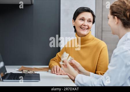 Portrait d'une femme mûre souriante parlant à un dentiste en clinique dentaire et consultant sur l'implantation dentaire, espace de copie Banque D'Images