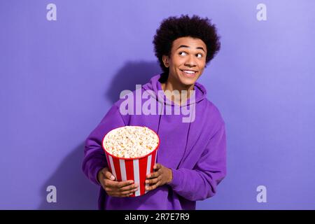 Portrait de la personne belle mains tenir le seau à pop-corn look vide espace beaming sourire isolé sur fond violet couleur Banque D'Images