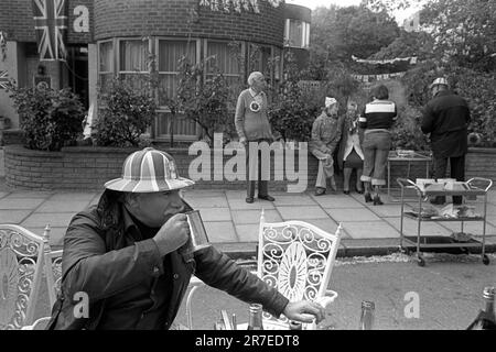 Reine Elizabeth II célébration du Jubilé d'argent 1977. Silver Jubilee Street Party, un homme plus âgé dans un chapeau en carton peint rouge, blanc et bleu boit une pinte de bière d'un tankard d'argent. Hampstead, nord de Londres, Angleterre vers juin 1977. Banque D'Images