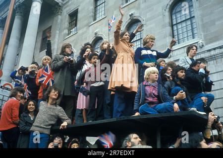 Reine Elizabeth II célébration du Jubilé d'argent 1977. Les foules de wishers se rassemblent et grimpent sur le toit d'un abri de bus pour obtenir une meilleure vue de la procession royale. Londres, Angleterre vers juin 1977. Banque D'Images