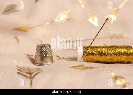 Bobine de fil d'or avec Thimble sur tissu de mousseline métallique Banque D'Images