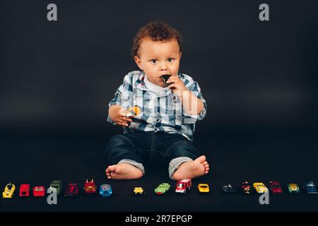 Studio photo d'adorable bébé africain de 9-12 mois jouant avec des mini voitures colorées Banque D'Images