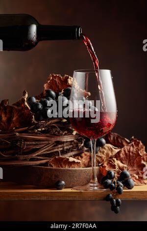 Le vin est versé dans un verre. Vin rouge et bouquet de raisins. Banque D'Images