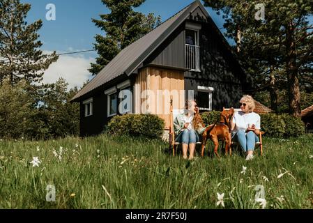 Mère et fille adulte avec chien se prélassant à l'extérieur Banque D'Images