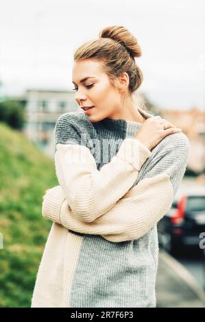 Portrait d'extérieur de la jeune jolie femme portant un pull gris chaud à col haut, temps froid Banque D'Images