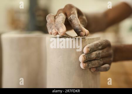 Céramiste africain ponçant un pot d'argile dans un banc de poterie Banque D'Images