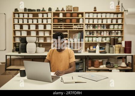 Chef d'atelier de céramique africaine utilisant un ordinateur portable dans un studio Banque D'Images