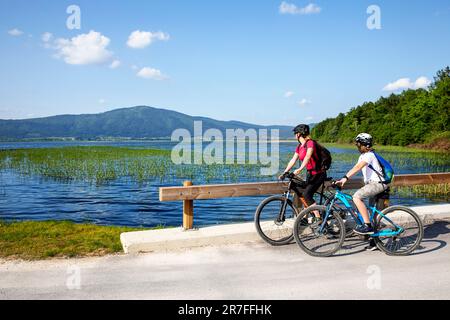 Mère et fils, touriste lors d'un voyage en famille à vélo lors d'une belle journée d'été sur le lac Cerknica, le plus grand lac karstique intermittent de slovénie Banque D'Images