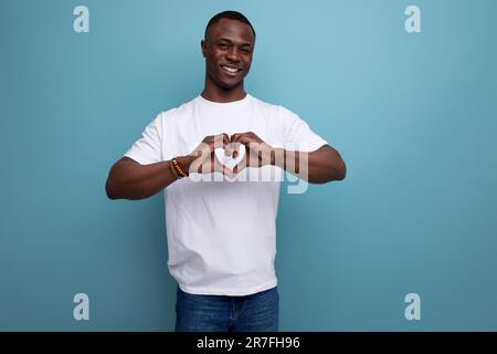 un jeune homme africain gentil dans un t-shirt blanc a plié ses mains sous la forme d'un coeur Banque D'Images