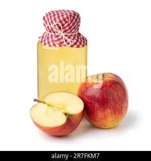 Bouteille avec du vinaigre de pomme maison en gros plan et une pomme en deux à l'avant isolée sur fond blanc Banque D'Images