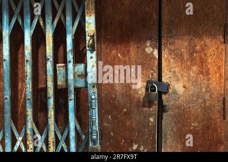 Ancienne serrure en acier doré et porte en acier endommagée et rouillée sur la porte en bois. Verrouillé sur une porte en bois avec un ancien volet métallique et une porte de porte pliante. Ancien BT Banque D'Images