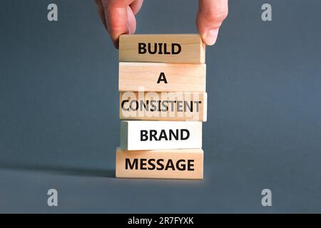 Symbole de message de marque cohérent. Les mots de concept créent un message de marque cohérent sur des blocs de bois. Main d'homme d'affaires. Magnifique fond gris. Affaires Banque D'Images