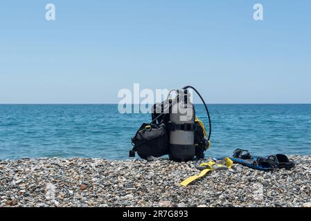 Équipement de plongée, y compris réservoir d'oxygène, palmes, lunettes, régulateur et poids sur la rive d'une plage rocheuse. Sports nautiques. Initiation à la plongée sous-marine Banque D'Images