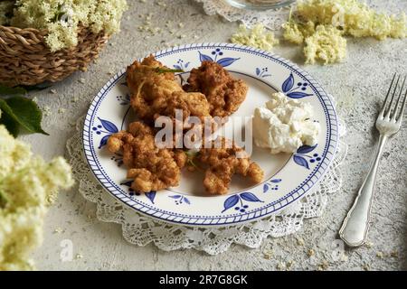 Une assiette de fleurs de sureau frites au printemps. Plante sauvage comestible. Banque D'Images