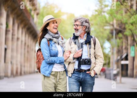 Joyeux couple plus âgé qui s'amuse à se promener en plein air en ville. Les retraités profitent d'une promenade touristique. Banque D'Images