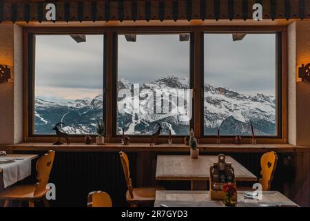 Une image des sommets enneigés vus à travers une fenêtre du restaurant Cortina d'Ampezzo en Italie Banque D'Images