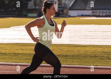 Jeune athlète caucasien, forte et musclée, course sur une piste sportive extérieure, tir moyen. Banque D'Images