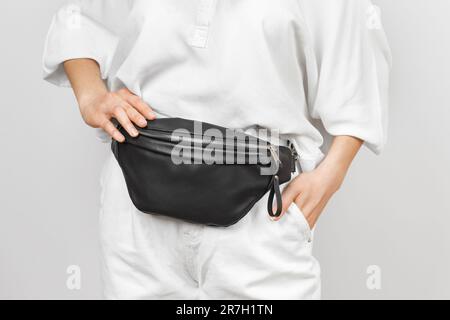 Sac de taille en cuir noir sur une femme portant un Jean et une chemise blancs. Articles d'accessoires en cuir faits main Banque D'Images