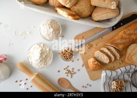 Pain frais avec farine de soja sur banc blanc et planche à découper avec tranches. Vue de dessus. Banque D'Images