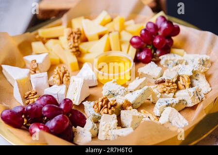 Plateau de fromages avec différents types de fromage, raisins, noix et miel Banque D'Images