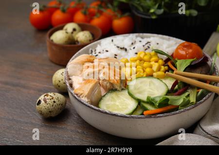 Délicieux poke bol avec viande, riz, légumes et légumes verts sur table en bois, gros plan Banque D'Images