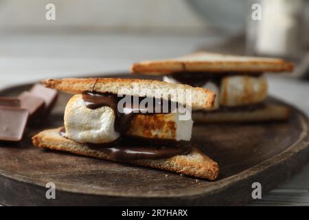 Délicieux sandwiches guimauves au chocolat sur plateau en bois, gros plan Banque D'Images