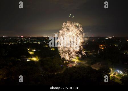 Vue aérienne des feux d'artifice lumineux qui explosent avec des lumières colorées sur les maisons de banlieue dans le quartier résidentiel lors des vacances de l'indépendance des États-Unis Banque D'Images