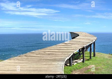 Longue passerelle en bois (le « Dock of Souls » de Chiloé) face à l'océan par temps clair Banque D'Images