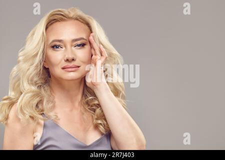 Élasticité de la peau de la femme mature. Une dame plus âgée tire la peau sur le temple. Banque D'Images