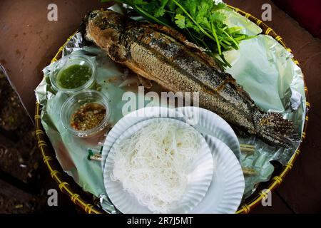 Cuisine thaïlandaise traditionnelle locale gastronomique rôti de poisson en forme de tête d'oie couvert avec une croûte de sel sur le poêle à charbon de bois avec des herbes de légumes et une sauce savoureuse épicée Banque D'Images