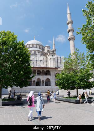 Les gens en tenue musulmane traditionnelle passent devant la mosquée Yeni Cami à Istanbul, en Turquie Banque D'Images