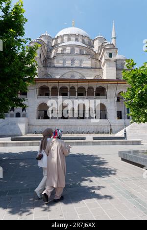 Les gens en tenue musulmane traditionnelle passent devant la mosquée Yeni Cami à Istanbul, en Turquie Banque D'Images
