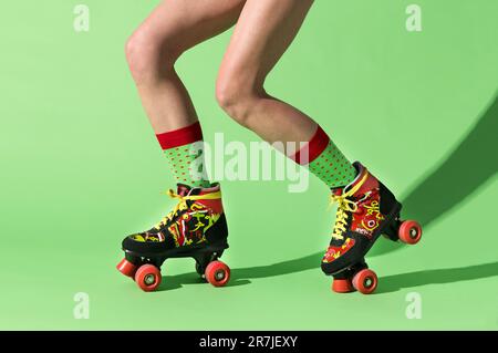 Vue latérale de jeunes femmes anonymes dans des chaussettes colorées équitation léger et robuste patins à roulettes réglables avec ombre sur la patinoire couleur lime Banque D'Images