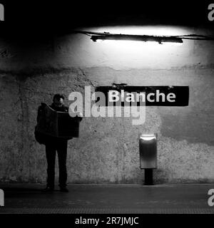 Homme lisant le journal à la station de métro Blanche à Paris, France Banque D'Images