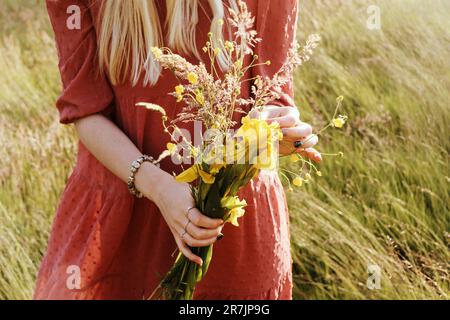 Bouquet de fleurs sauvages jaunes dans les mains d'une femme Banque D'Images