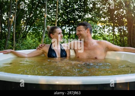 couple romantique se détendant dans le bain à remous extérieur au feu de bois dans la forêt Banque D'Images