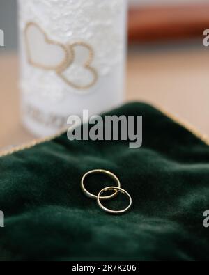 Un gros plan de deux anneaux de mariage placés sur un tissu de velours vert. Banque D'Images